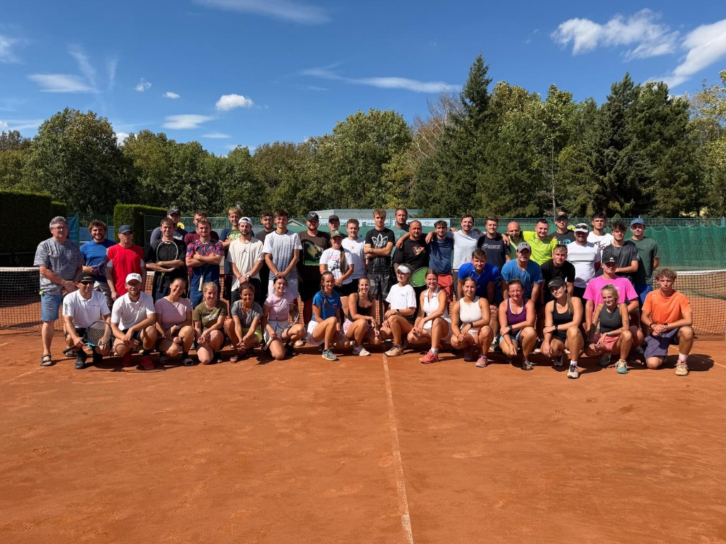 Group of around 50 tennis coaches on a clay court